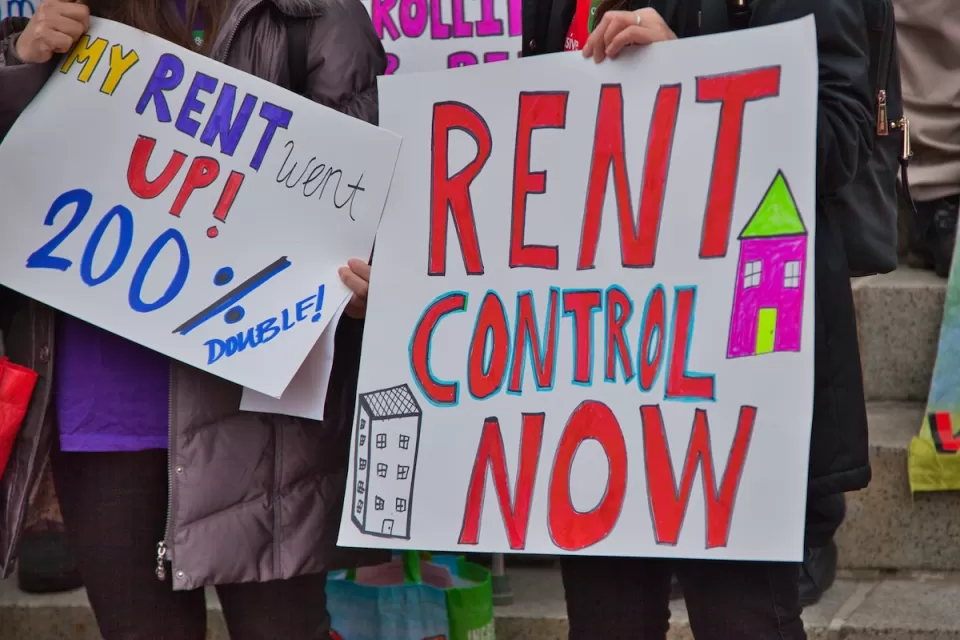 Close-up of "Rent Control Now" sign being held up at a protest.